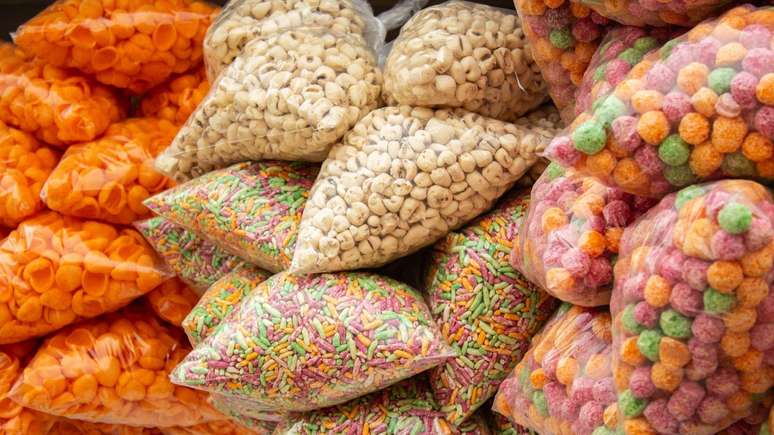 Cereais coloridos embalados em sacos transparentes e empilhados. 