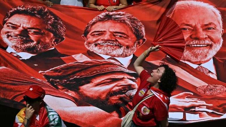 Uma apoiadora do presidente e candidato &agrave; reelei&ccedil;&atilde;o Luiz In&aacute;cio Lula da Silva faz um gesto ao lado de uma enorme faixa com imagens que retratam diferentes momentos de sua trajet&oacute;ria durante ato de campanha na v&eacute;spera da elei&ccedil;&atilde;o geral, em S&atilde;o Paulo, em 3 de outubro de 2026.