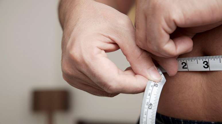 Pessoa mede a barriga com fita m&eacute;trica. 
