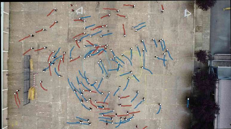 Vista a&eacute;rea de um p&aacute;tio de escola, com pontos coloridos representando pessoas em movimento.