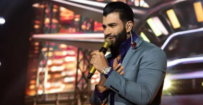 Gusttavo Lima usando terno com um microfone na m&atilde;o