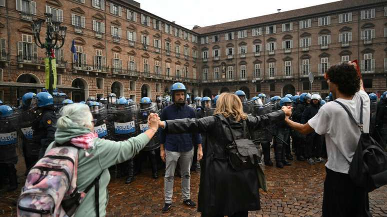 Professores se posicionam entre policiais de choque e estudantes durante protesto do "No Meloni Day", em Turim; manifestantes cobram melhorias na educa&ccedil;&atilde;o e protestam contra o aumento do custo de vida.