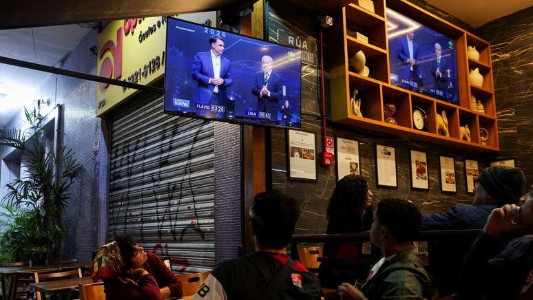 Pessoas assistem ao debate presidencial na televis&atilde;o entre o candidato &agrave; presid&ecirc;ncia do Brasil, Fl&aacute;vio Bolsonaro, do Partido Liberal (PL), e o presidente Luiz In&aacute;cio Lula da Silva, do Partido dos Trabalhadores (PT), em S&atilde;o Paulo, Brasil, em 18 de outubro de 2026