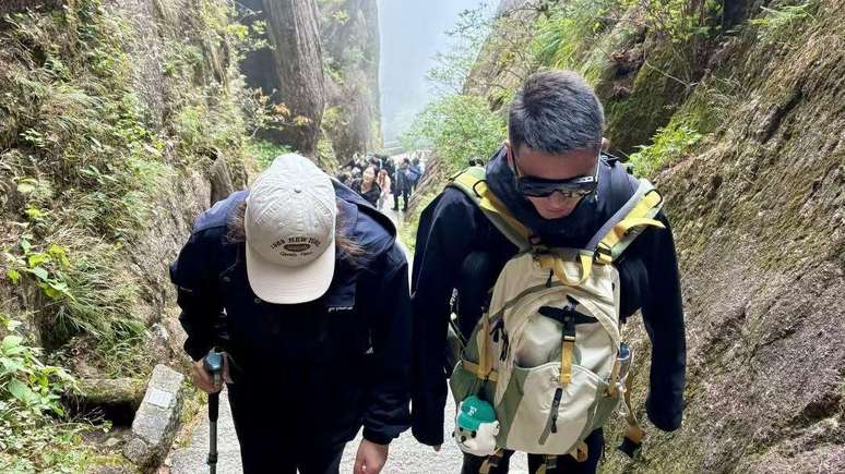 O guia de montanhas Wang Zhoutao acompanha um cliente nas &iacute;ngremes escadas da montanha Huangshan