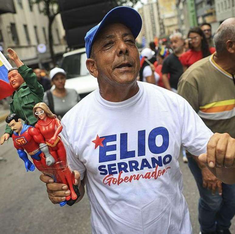Simpatizante do governo venezuelano, com bonecos de Nicol&aacute;s Maduro e Cilia Flores como super-her&oacute;is.