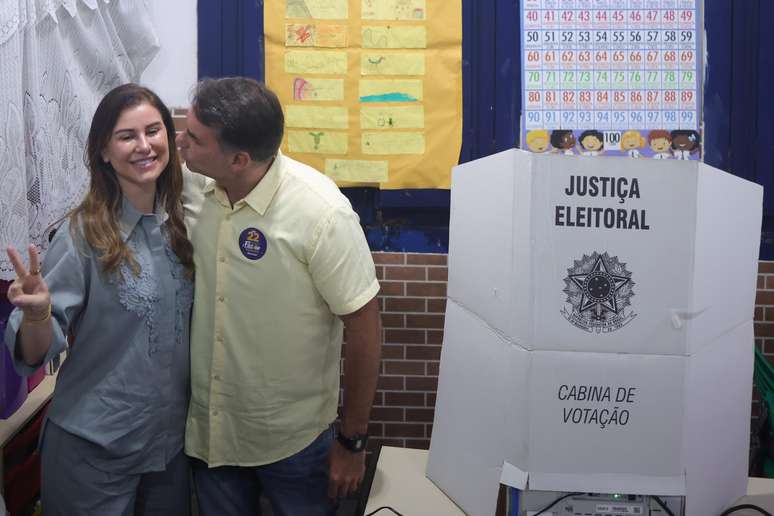  O candidato Fl&aacute;vio Bolsonaro (PL), beija a esposa, Fernanda, ap&oacute;s registrar seu voto na Escola Municipal Bar&atilde;o Homem de Mello, localizada no bairro de Vila Isabel, na Zona Norte do Rio de Janeiro, na manh&atilde; deste domingo, 25.