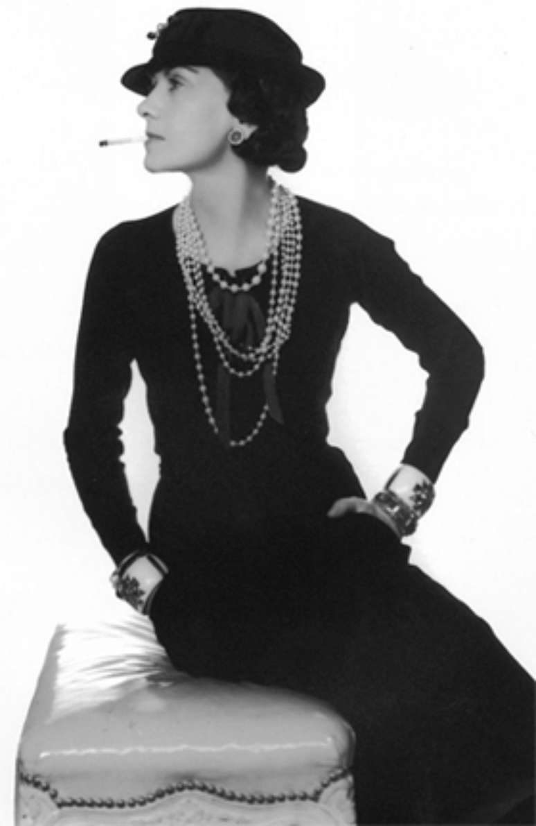 Coco Chanel de vestido preto e p&eacute;rolas 