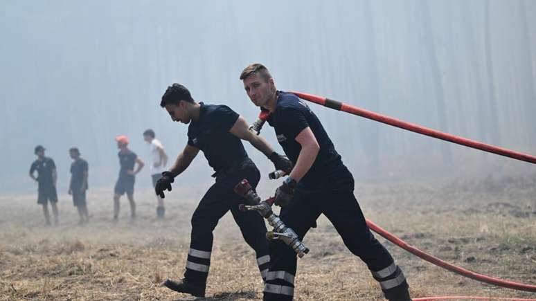 Bombeiros posicionam suas mangueiras para combater inc&ecirc;ndios perto de La Berle-de-Cassy, ​​durante os inc&ecirc;ndios florestais que assolam o sudoeste da Fran&ccedil;a, em julho de julho de 2026.