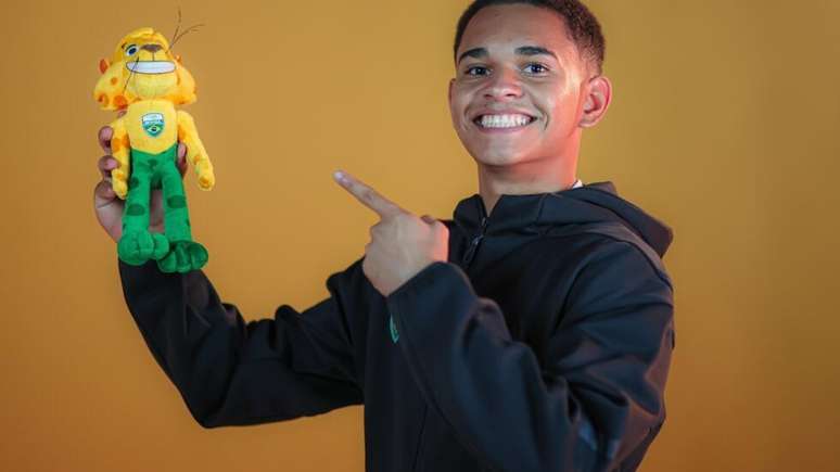 Jogador de badminton Klecivan Zaidan, vice-campe&atilde;o pan-americano j&uacute;nior, aponta para o mascote dos Jogos Ol&iacute;mpicos da Juventude.