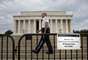 1&ordm; de outubro - Policial faz a seguran&ccedil;a atr&aacute;s de barricada com placa em que se l&ecirc; "Por causa da paralisa&ccedil;&atilde;o do governo federal todos os parques nacionais est&atilde;o fechados", em frente ao Lincoln Memorial, em Washington