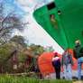 Três pessoas, vestindo jeans e jaquetas casuais, estão de pé, observando um enorme navio porta-contêineres verde que encalhou em terra firme. Uma casa parece pequena e está ao lado do navio. Foto: EPA / BBC News Brasil