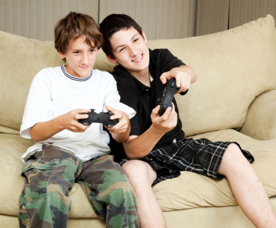 Menina olha como o menino joga o jogo online. dois meninos jogam jogos  online em quarentena. rapazes sorriem e