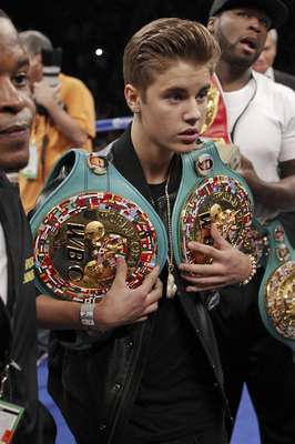 Justin Bieber carga los títulos de Floyd Mayweather Jr. previo a su pelea con Miguel Cotto en Las Vegas. (AP Photo/Eric Jamison)