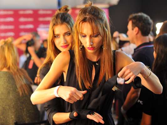 Modelos se aprontam em backstage antes de desfilar