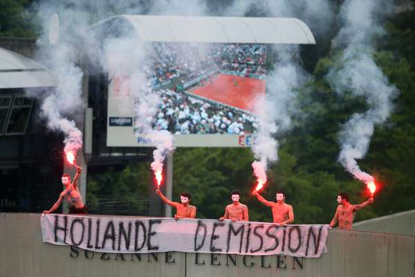 Protesters light flares and unfurl a banner on the top of Court Suzanne Lenglen as Rafael Nadal of Spain and David Ferrer of Spain compete on Court Philippe Chatrier