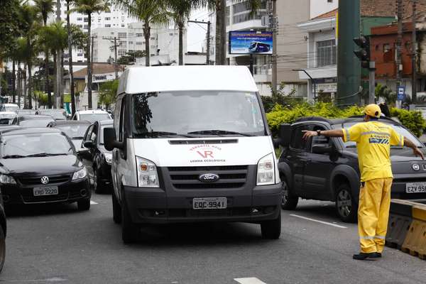 Funcionário a serviço da Dersa orienta fila de veículos para balsa em Cubatão, que ficou congestionada após bloqueio na rodovia
