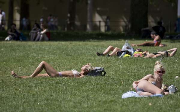 30 de junho - Inglaterra: mulheres aproveitam a chegada do verão para se bronzearem nos parques