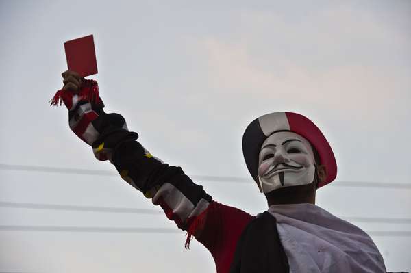1º de julho - Manifestante vestido com a máscara de Guy Fawkes exibe cartão vermelho para o presidente Mohamed Mursi durante protesto na Praça Tahrir. Após um grande ato no domingo (dia 30), centenas de milhares de pessoas voltaram às ruas exigindo que Mursi renunciasse ao cargo