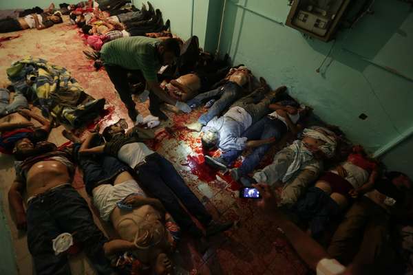 Corpos são vistos espalhados pelo chão de hospital após tiroteio em frente ao prédio da Guarda Republicana em Nasser, subúrbio de Cairo. Seguidores de o presidente deposto Mohamed Mursi e da Irmandade Muçulmana acusam o Exército de abrir fogo contra uma manifestação pacífica. Os militares dizem que o tiroteio foi perpetrado por terroristas que tentaram invadir o prédio