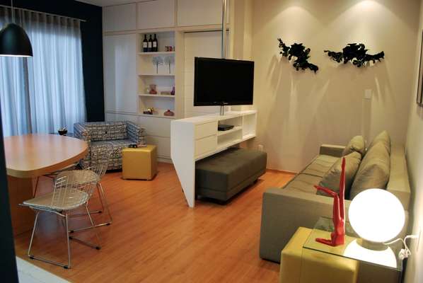 Neste projeto de 48m², a disposição da sala de TV foi alterada, com inclusão de uma marcenaria com suporte giratório para atender aos três ambientes