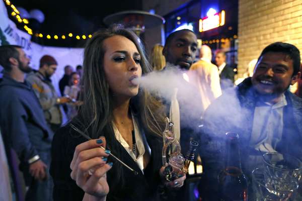 Jovem fuma maconha em uma festa de Réveillon que celebra o início da venda da droga em Denver