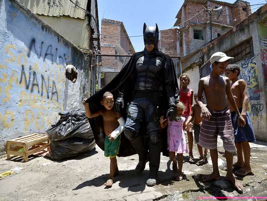 Homem fantasiado de Batman alegra as crianças no momento da retirada dos moradores da Vila do Metrô