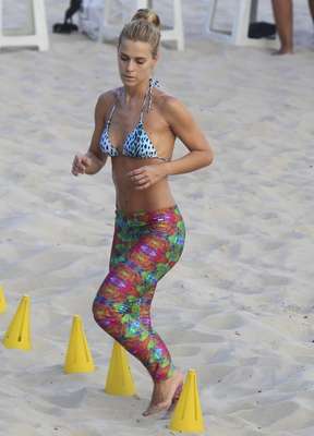 A atriz Carolina Dieckmann pratica exercícios na praia. No entanto, em vez do biquíni, ela poderia ter escolhido um top para dar mais sustentação aos seios