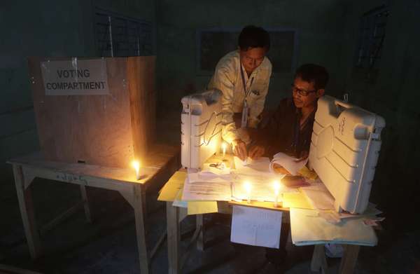 Policiais verificam os materiais relacionados às eleições e as urnas eletrônicas, sob a luz de velas, em um dos centros de votação da Índia