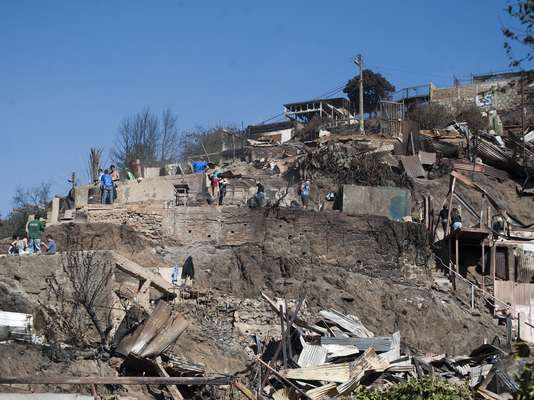Cientos de vecinos del Cerro La Cruz trabajan en la zona removiendo los escombros que dejó el brutal incendio que afectó a la zona desde la tarde del sábado.