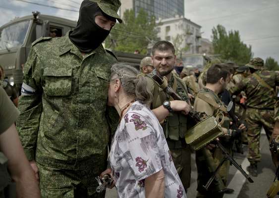 Idosa se "aconchega" no corpo de um paramilitar pró-Rússia na praça Lenin, em Donetsk