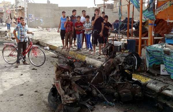 06 de junho - Jovens iraquianos observam os danos causados após a explosão de um carro-bomba na cidade de Kirkuk