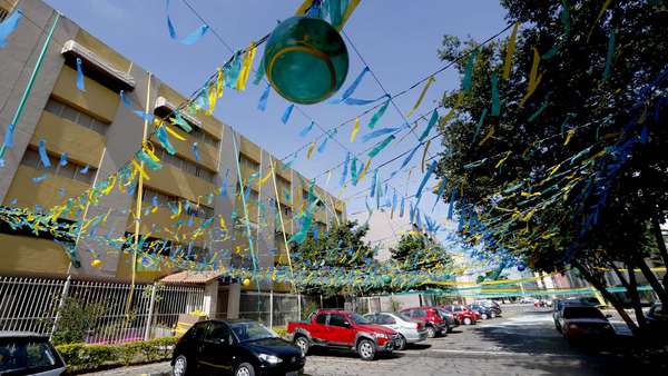 Um conjunto residencial em Brasília está coberto de verde e amarelo: bandeirinhas e pinturas são vistas por toda parte. A sede do Estádio Mané Garrincha, que recebeu Colômbia x Costa do Marfim na última quinta-feira, agora se prepara para o jogo do Brasil na próxima segunda-feira, contra Camarões, às 17h