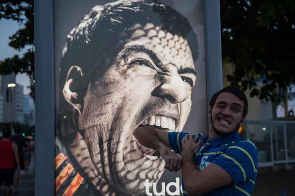 Uma placa publicitária com a foto do jogador uruguaio Luis Suárez, suspenso pela Fifa por nove partidas oficiais da seleção e por quatro meses de qualquer atividade relacionada ao futebol pela mordida dada no zagueiro italiano Chiellini, virou atração turística na praia de Copacabana, na zona sul do Rio de Janeiro. Torcedores e turistas encenam mordidas com a foto do atacante, que vai ficar de fora do resto da Copa no País