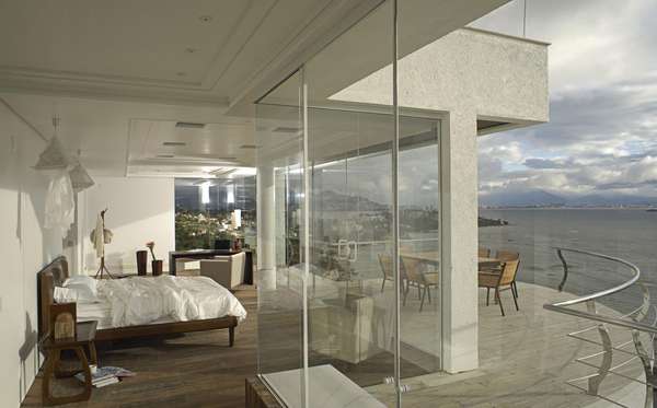 Todo envidraçado, este quarto de casal projetado por Mantovani e Rita privilegia a vista para o mar e o design clean