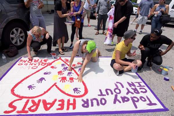Pessoas marcam com suas mãos cartaz em homenagem aos mortos no massacre na boate Pulse, em Orlando (EUA)