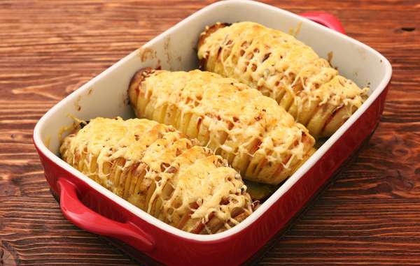 A receita é simples e deliciosa! Ingredientes: batatas, manteiga para pincelar por cima e recheio. Modo de preparo: laminar as batatas com a faca de modo que não chegue até o final, caso contrário, vai virar chips. Depois coloque o recheio dentro, pode colocar mais coisas além do queijo, por exemplo, bacon e temperos, ok? Dê o último toque pincelando toda a superfície com manteiga derretida. Para finalizar, só enfileirar as batatas em uma assadeira e levar para o forno em fogo alto por uma hora.