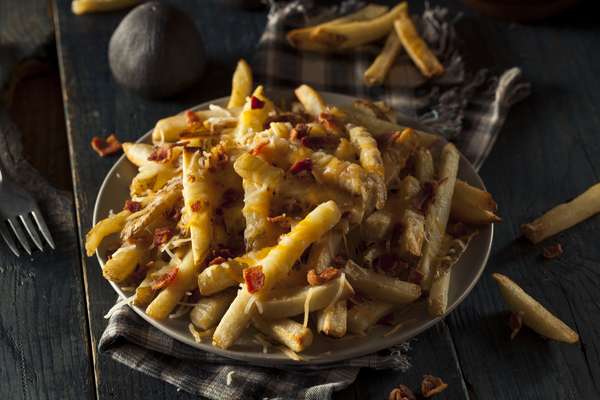 Batata Frita do Outback*Receita do blog Pilotando um Fogão Ingredientes 3 fatias de bacon picadas Papel toalha 80g de queijo prato/lanche ralado grosso 80g de queijo mussarela ralado grosso 5 batatas médias (de preferência batatas com casca marrom/rosada) Óleo para fritar Sal Pimenta do reino Modo de preparo Inicie o preparo tostando o bacon já em pedacinhos. Isso pode ser feito numa panela ou frigideira sem a adição de azeite ou óleo, até que fique bem torrado. Também é possível fazer no micro-ondas ou fritadeira. Rale os queijos e reserve. Lave as batatas, descasque e corte em palitos finos e compridos. Lave novamente, coloque sobre um pano de prato limpo e seco e seque bem todas as batatas. Frite as batatas numa panela grande cheia de óleo. Depois escorra as batatas quando elas estiverem levemente douradas. Coloque-as em papel toalha para secar bem. Com as batatas ainda sobre o papel toalha, coloque sal e pimenta, e misture bem. Transfira para o prato ou travessa onde irá servir (deve ser um prato que possa ir ao forno). Coloque os queijos ralados, que devem estar misturados, por cima das batatas. Polvilhe mais pimenta e leve ao forno preaquecido a 200°C, por cerca de 4 ou 5 minutos, ou até que os queijos derretam. Coloque o bacon picadinho e torrado sobre as batatas gratinadas e sirva. Dica: você também pode incluir cheddar na receita, na mesma quantidade dos outros queijos.