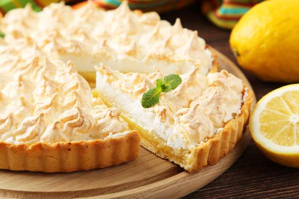 Torta de Limão e Iogurte*Receita por Gold Editora Ingredientes 2 xícaras (chá) de farinha de trigo 5 colheres (sopa) de coco seco ralado (30 g) ¾ de xícara (chá) de açúcar 1 ovo 100 g de manteiga gelada picada Recheio 1 lata de leite condensado ¾ de xícara (chá) de suco de limão 1 colher (chá) de raspas de limão para salpicar 1 pote (170 g) de iogurte natural 1 colher (chá) de gelatina em pó incolor (4 g) hidratada e derretida em 1 colher (sopa) de água Corante alimentício verde em gel (opcional) Cobertura 1 caixinha (200 ml) de creme para chantili bem gelado 300 g de chocolate branco picado Raspas de limão para decorar Modo de preparo Misture a farinha com o coco e o açúcar. Adicione o ovo e a manteiga e amasse rapidamente até formar uma bola lisa e homogênea. Envolva em filme plástico e deixe em repouso na geladeira por 20 minutos. Abra a massa e forre a base e a lateral de uma fôrma redonda de fundo removível (23 x 5 cm). Asse em forno médio preaquecido (180°C) por 35 minutos ou até dourar bem. Deixe esfriar. Recheie a torta e leve à geladeira por cerca de 2 horas ou até firmar. Cubra a torta gelada de forma decorativa, salpique as raspas de limão, desenforme e sirva em seguida. Recheio: Misture os 4 primeiros ingredientes até homogeneizar. Adicione a gelatina ainda quente e misture. Se desejar, junte corante alimentício a gosto e mexa bem para homogeneizar. Cobertura: Reserve ¼ de xícara (chá) do creme para chantili e mantenha o restante na geladeira. Derreta o chocolate branco no micro-ondas, em potência média, por 2 minutos, mexendo na metade do tempo, até ficar liso. Agregue o creme reservado e misture bem. Na batedeira, bata o restante do creme gelado até espessar. Retire 2 colheres (sopa) deste chantili e junte à mistura de chocolate. Incorpore delicadamente o restante do chantili e coloque em saco de confeitar com bico liso médio ou grande.