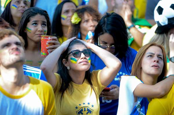 Torcedora leva as mãos à cabeça enquanto torce pelo Brasil