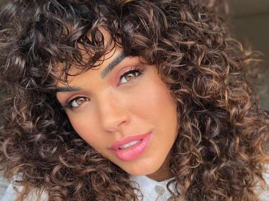Giovana Cordeiro mantem uma franja cacheada reta e com as pontas desfiadas um pouco acima das sobrancelhas