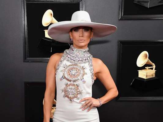 Chapéu no tapete vermelho? Temos! Jennifer Lopez foi quem apostou no acessório para combinar com o vestido longo off white no Grammy Awards 2019