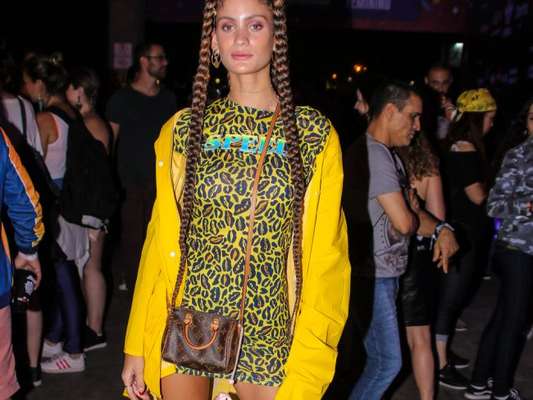 Looks dos famosos do Lollapalooza: Laura Fernandez usou mix de animal print com fundo amarelo, casaco amarelo vibrante oversized e dad sneaker branco. As boxer braids deixaram o visual com mais estilo ainda