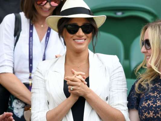 Meghan Markle assistiu a amiga Serena Williams em Wimbledon (em julho de 2019): o look incuía jeans, t-shirt preta e chapéu panamá, mas o que chamou a atenção foi o cordão em ouro com a letra 'A', de Archie
