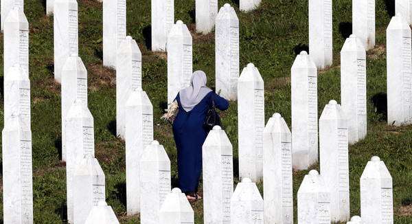 Mulher muçulmana reza em cemitério para vítimas do massacre de Srebrenica, em 11 de julho de 2020