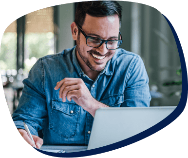 homem usando óculos e camisa jeans sorrindo e mexendo no computador homem usando óculos e camisa jeans sorrindo e mexendo no computador