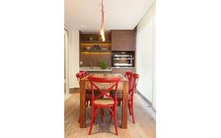 1. Cantinho do churrasco pequeno decorado com mesa rústica e cadeira vermelha – Foto: Liliana Zenaro