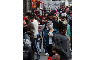 Mulher usando máscara protetora e protetor facial fala ao telefone enquanto pessoas caminham em uma popular rua comercial em meio ao surto de Covid-19 em São Paulo, Brasil, 15 de julho de 2020