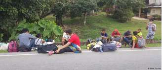 Grupo de venezuelanos na Colômbia descansa na beira da estrada, durante caminho de volta à Venezuela
