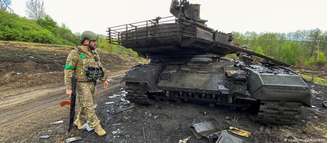 Soldado ucraniano observa tanque russo destruído na região de Kharkiv