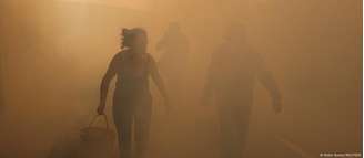 Pessoas caminham em meio à fumaça de um incêndio florestal em Vilarinho, em Portugal